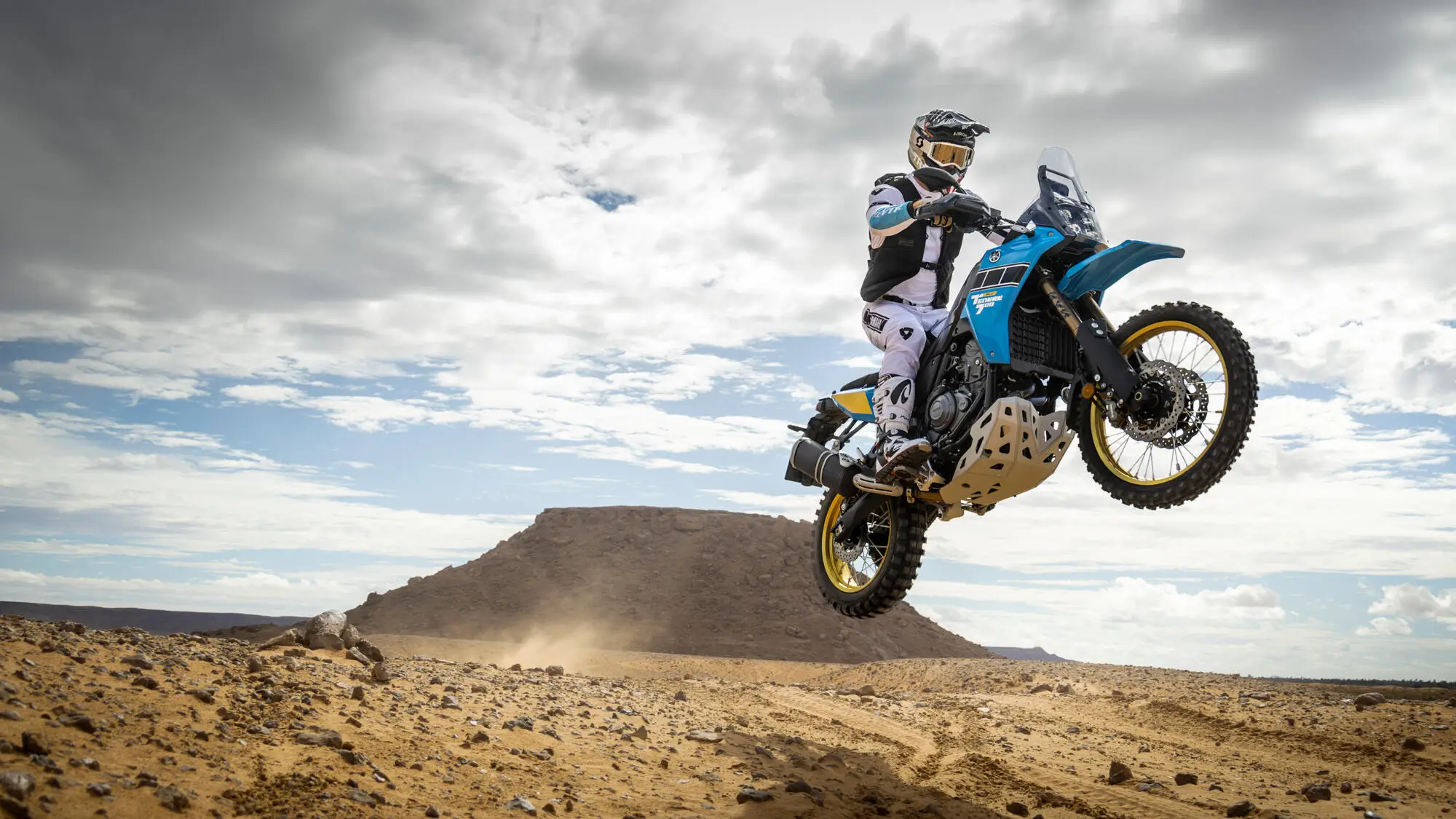 Ein Motorradfahrer springt mit einer Yamaha XTZ700SPR über eine sandige Wüstenlandschaft.