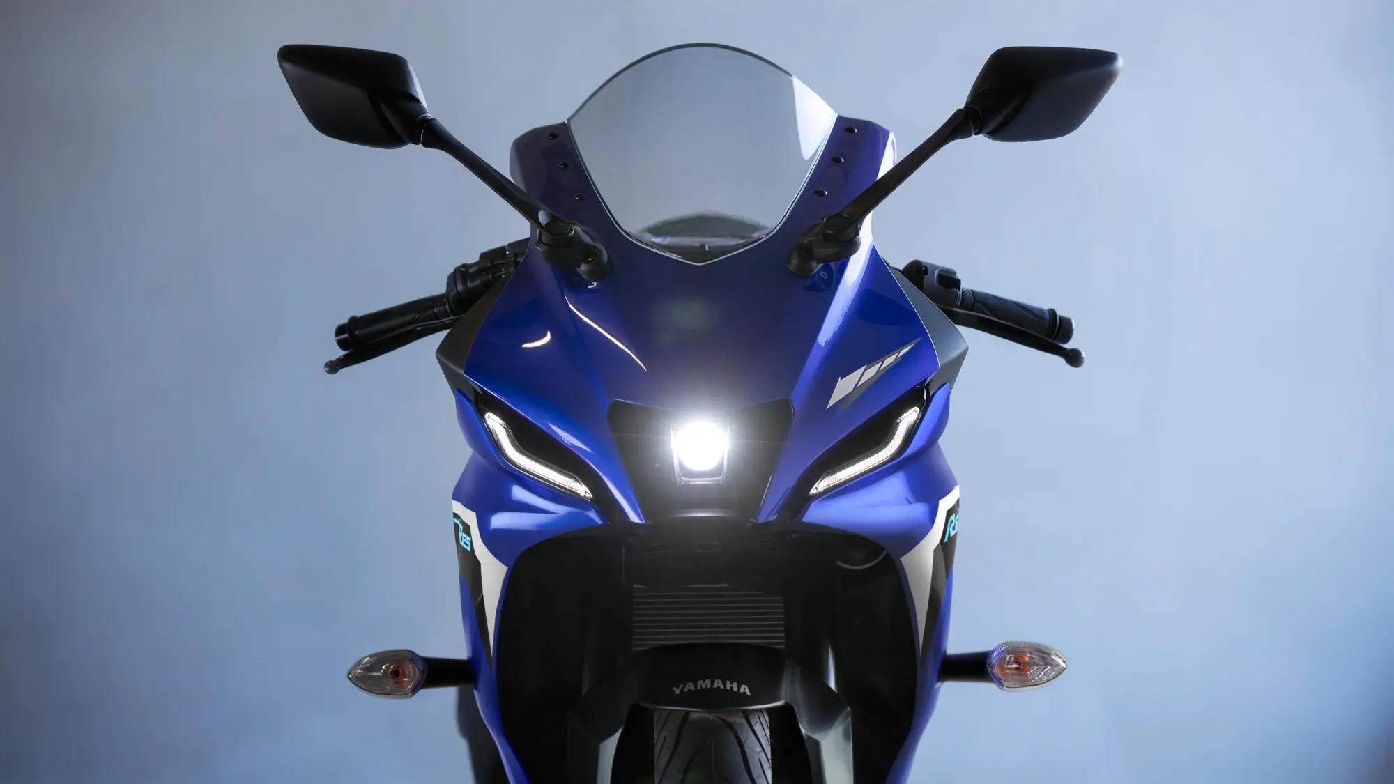 Frontansicht einer blauen Yamaha YZF-R125 mit eingeschaltetem Scheinwerfer.