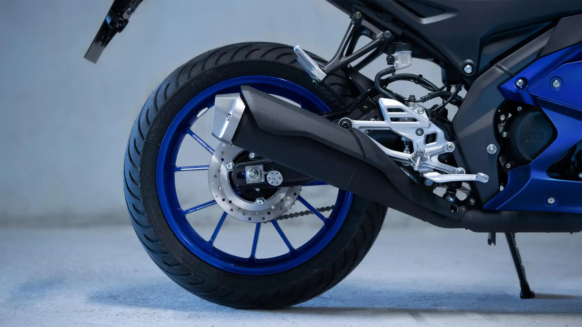 Hinterrad und Auspuff einer blauen Yamaha YZF-R125.