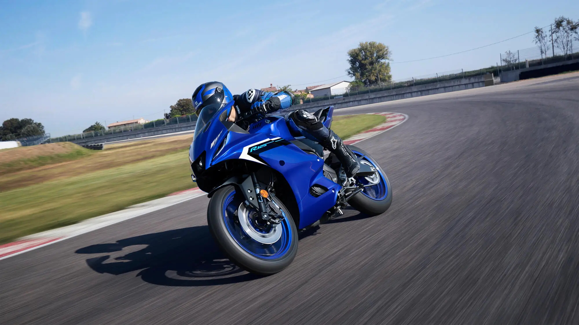 Fahrer auf einer blauen Yamaha YZF-R125 in Schräglage auf einer Rennstrecke.