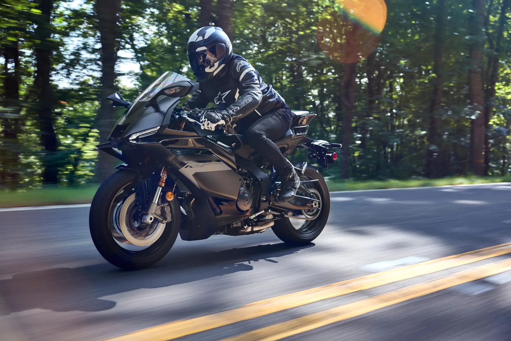 Ein Motorradfahrer fährt eine Yamaha YZF900R9 auf einer Waldstraße.