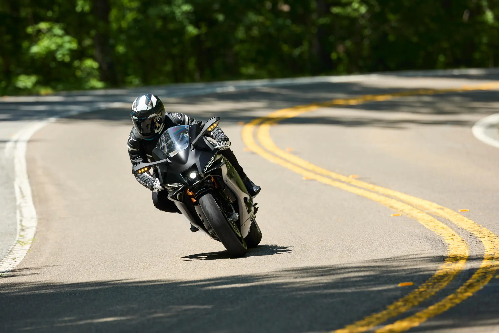 Ein Motorradfahrer auf einer Yamaha YZF900R9 fährt eine kurvige Straße entlang.