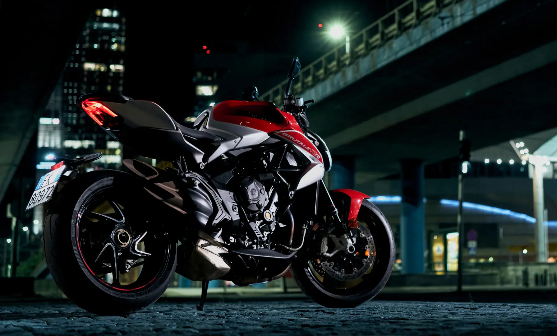4 Ein rotes und weißes MV Agusta Brutale Motorrad steht nachts unter einer Brücke.