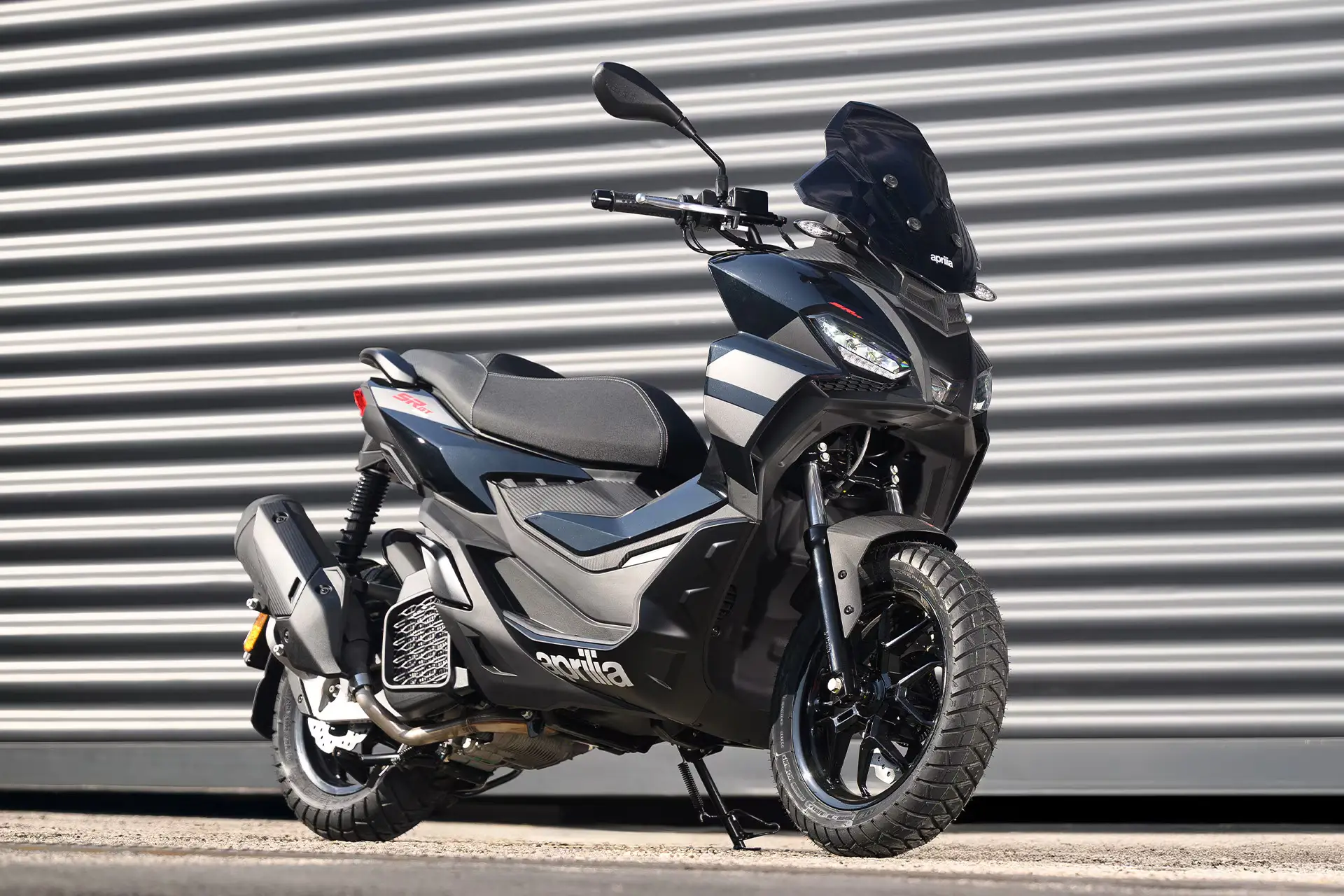 Aprilia SR GT 125 Roller vor einem metallischen Hintergrund.