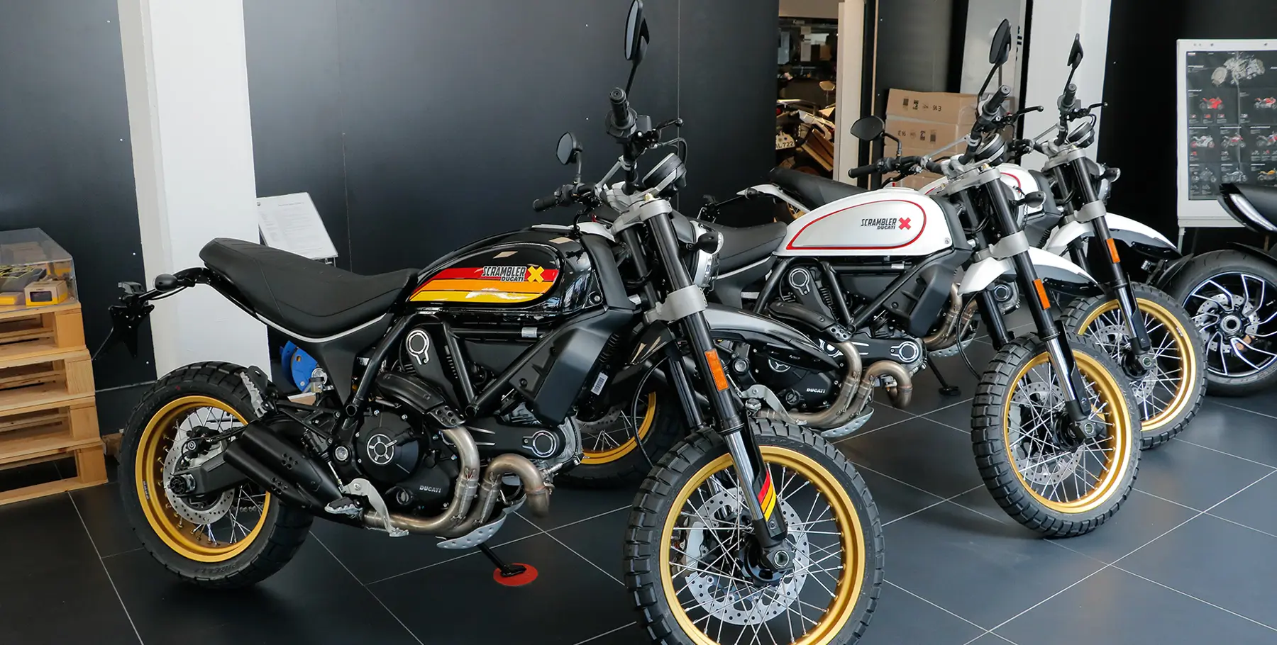 Drei Ducati Scrambler Motorräder in einer Ausstellung.