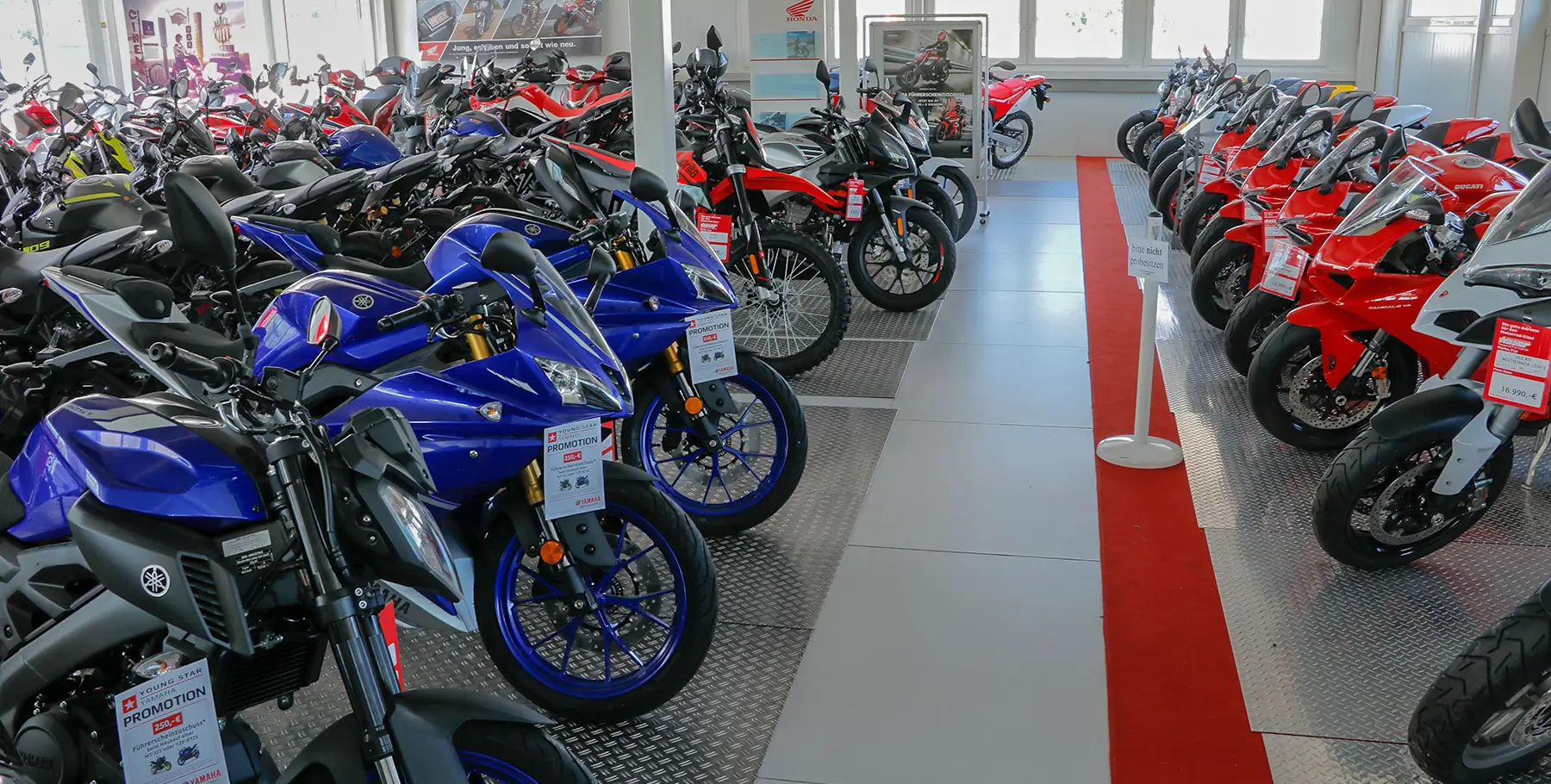 Ausstellung_32 Ausstellung von Motorrädern verschiedener Marken, darunter Yamaha und Ducati, in einem Showroom.