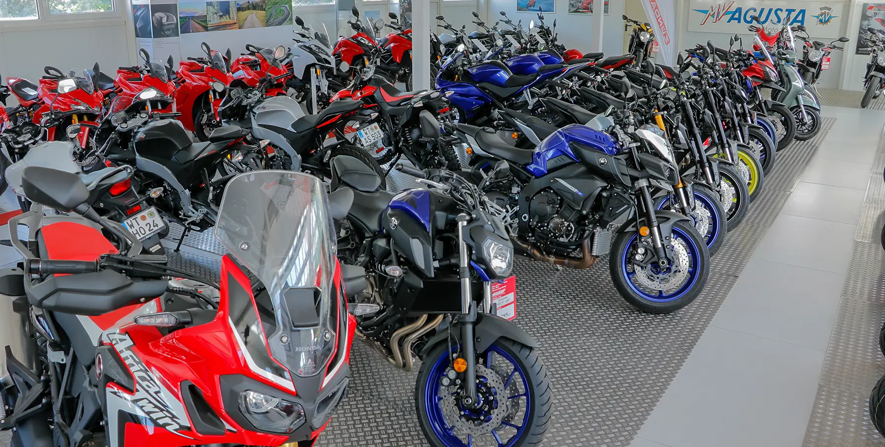 Ausstellung_35 Eine Ausstellungshalle voller Motorräder, darunter Modelle von Honda und Yamaha.