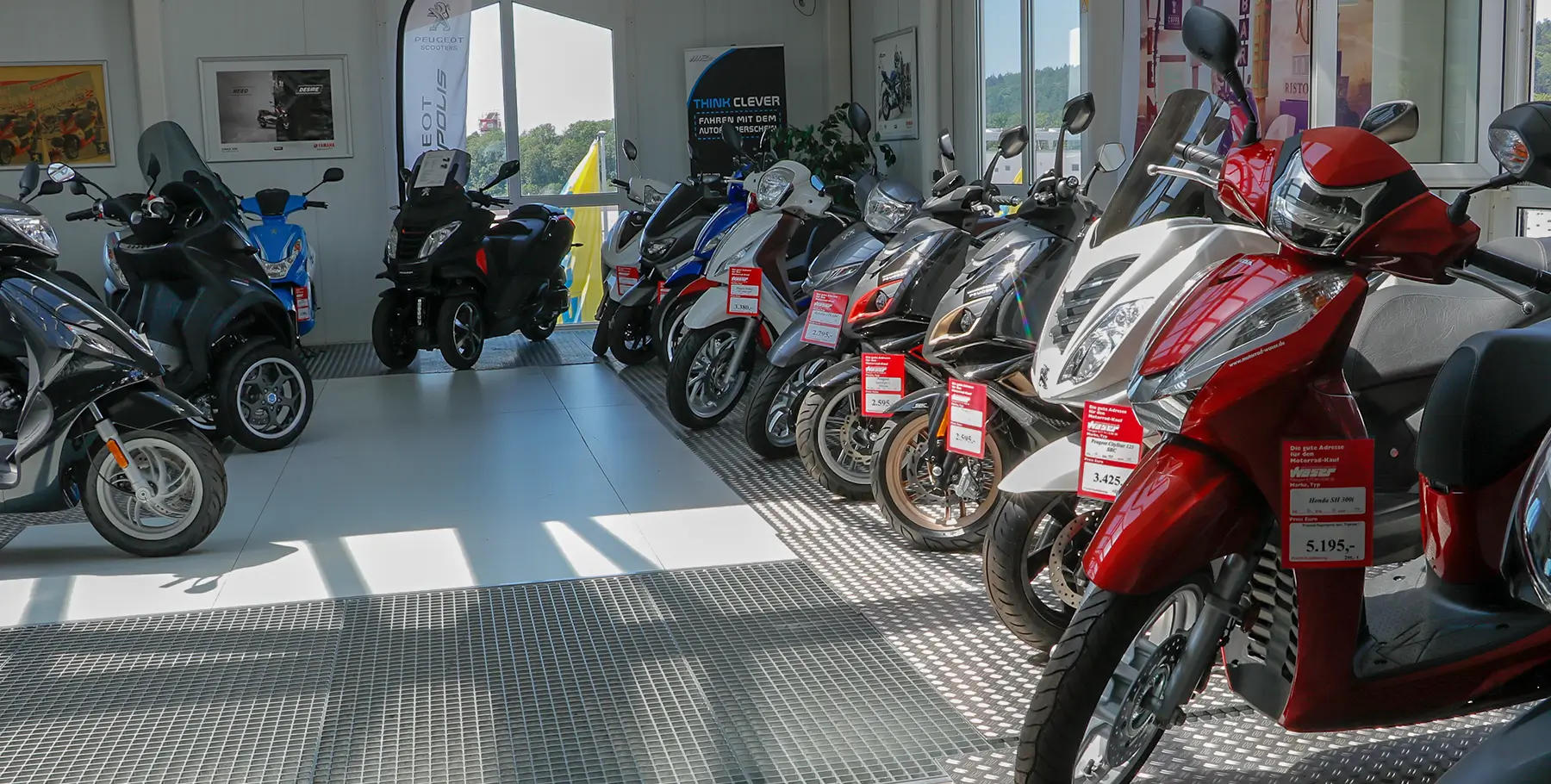 Eine Reihe von Rollern und Motorrädern steht in einem Ausstellungsraum.