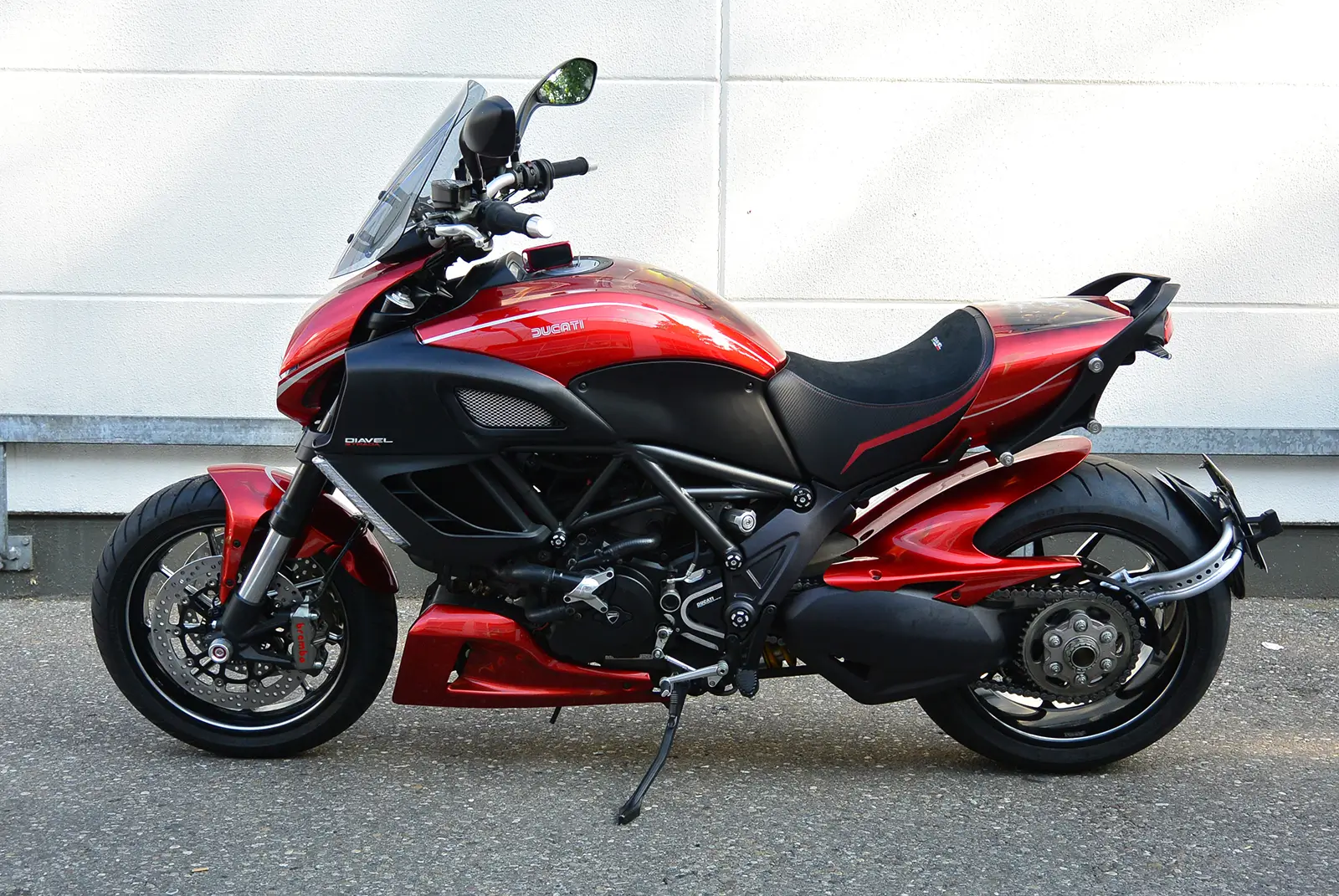 Ein rotes Ducati Diavel Motorrad steht seitlich auf einem Asphaltboden.