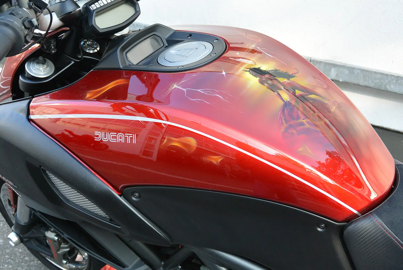 Roter Ducati-Motorradtank mit Airbrush-Kunstwerk und Blitzmotiv.