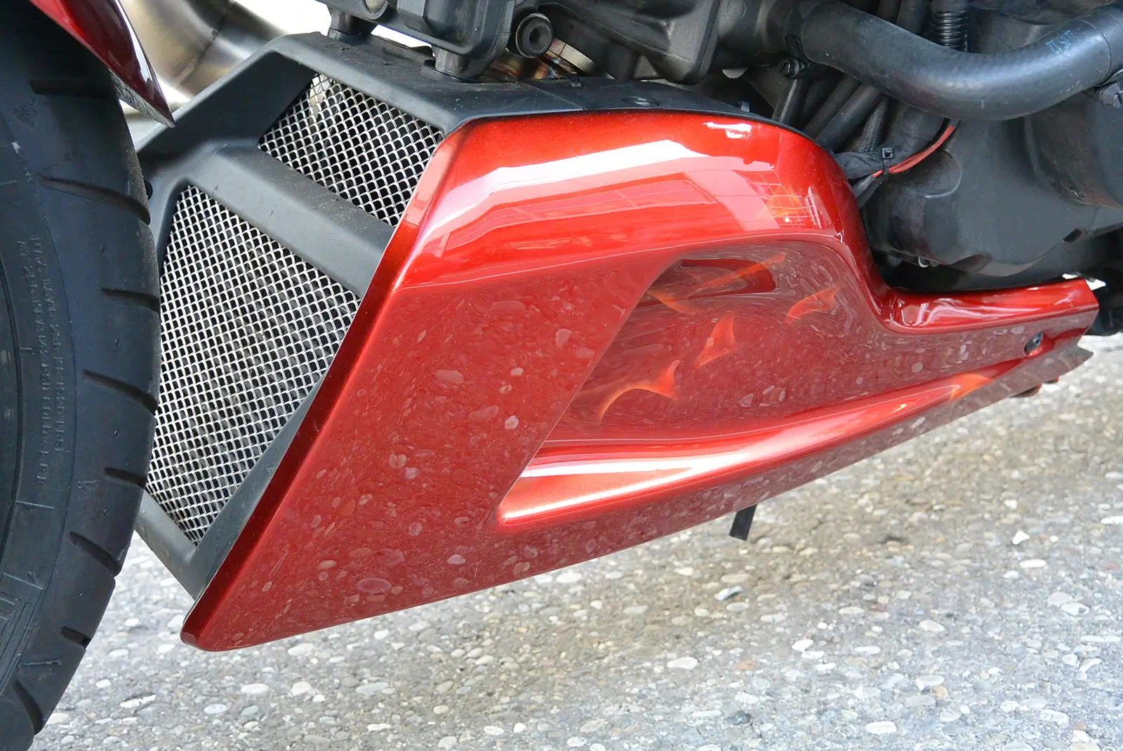 Roter Motorradmotor mit Lüftungsgitter und Auspuffdetail.