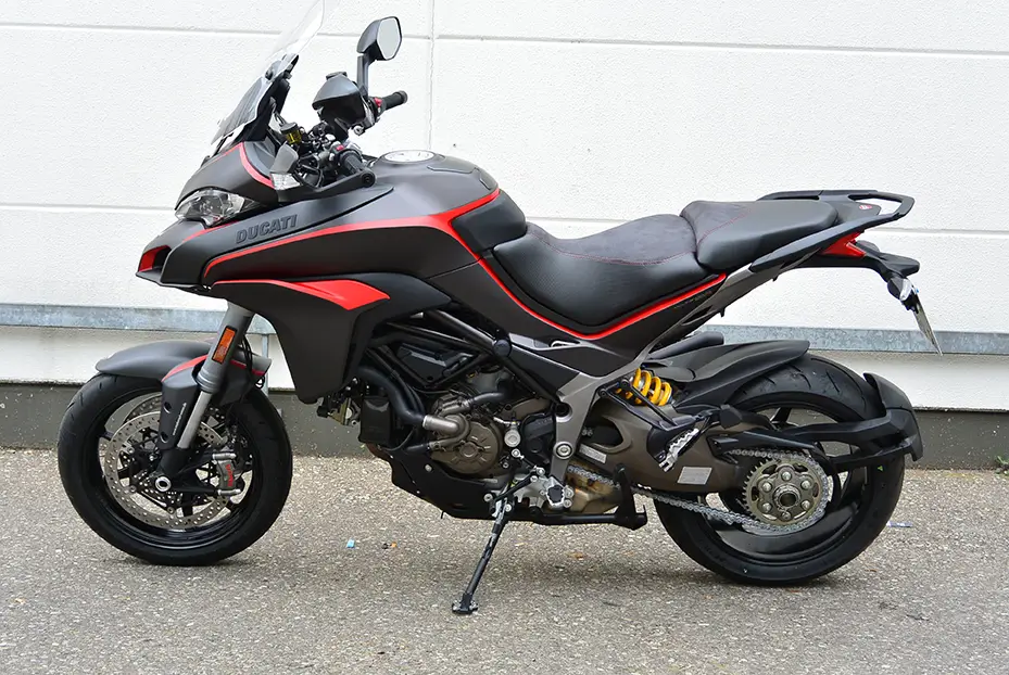 Ein schwarzes und rotes Ducati-Motorrad, Modell Multistrada, steht seitlich auf einem Parkplatz.