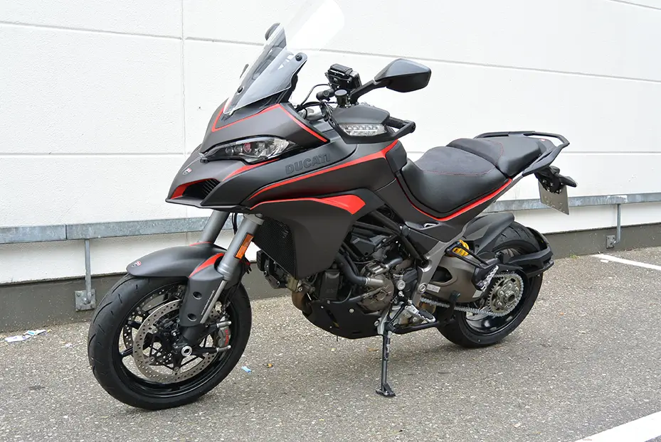 Ein schwarzes Ducati Motorrad mit roten Akzenten steht auf einem Parkplatz.
