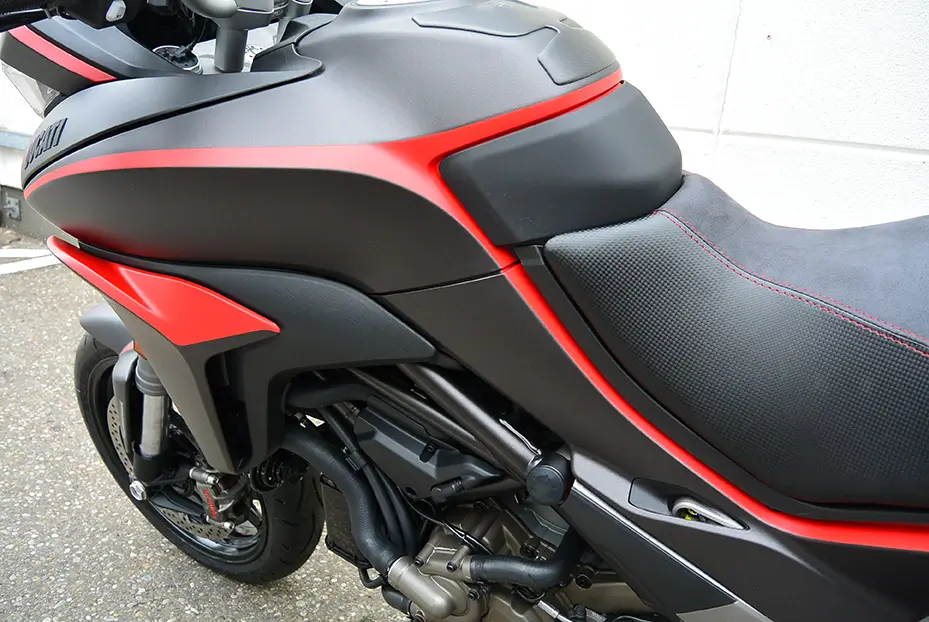 Motorrad der Marke Ducati mit schwarzem und rotem Design, seitliche Nahaufnahme.