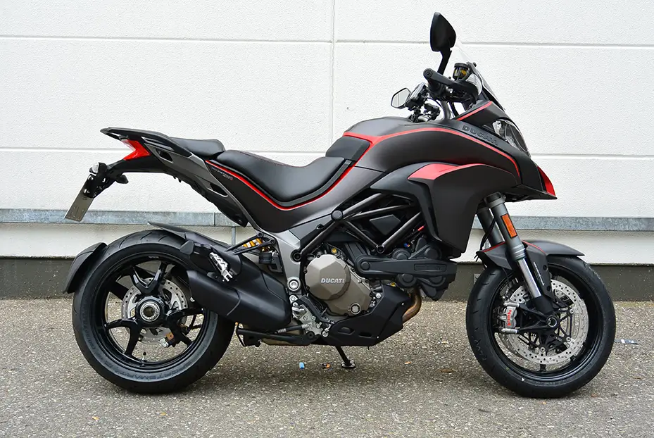 Ein schwarzes Ducati-Motorrad, Modell Multistrada, steht seitlich vor einer weißen Wand.