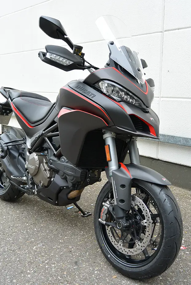 Ducati Motorrad, Modell Multistrada, in Schwarz mit roten Akzenten, seitlich auf einem Parkplatz.