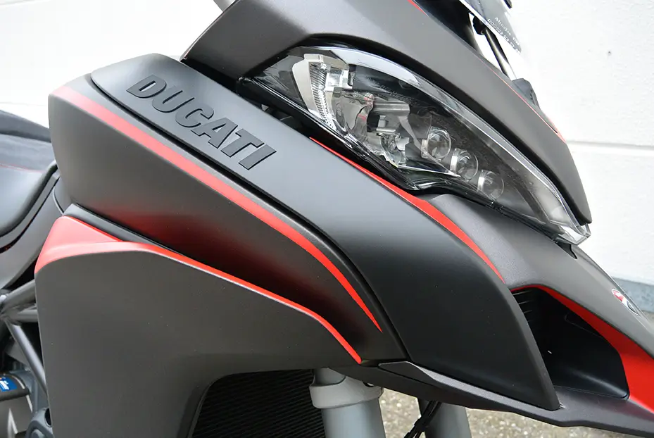 Nahaufnahme eines Ducati-Motorrad-Scheinwerfers mit rotem Streifen.
