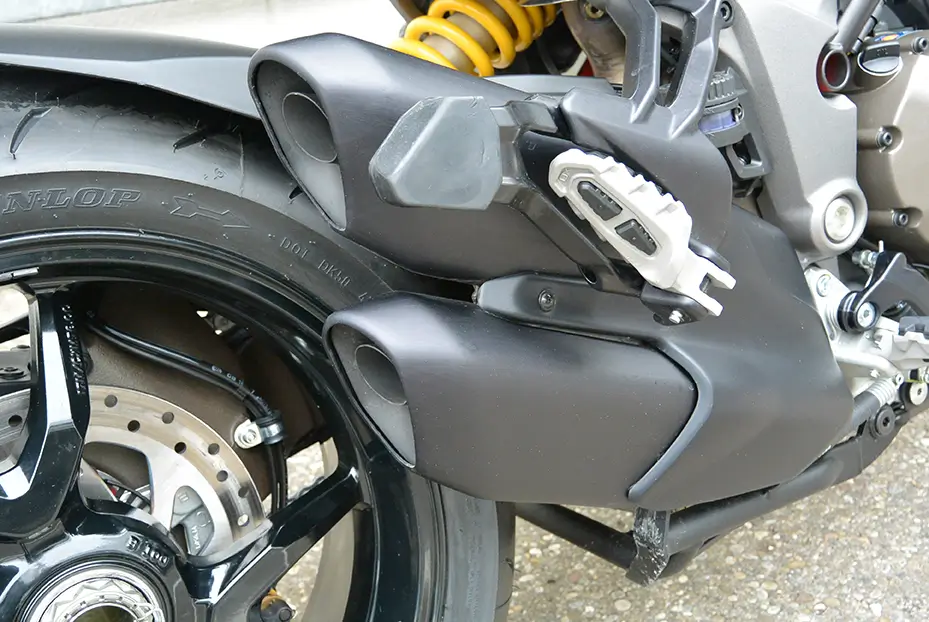 Hinterrad und Auspuff eines Motorrads, möglicherweise ein Yamaha-Modell.