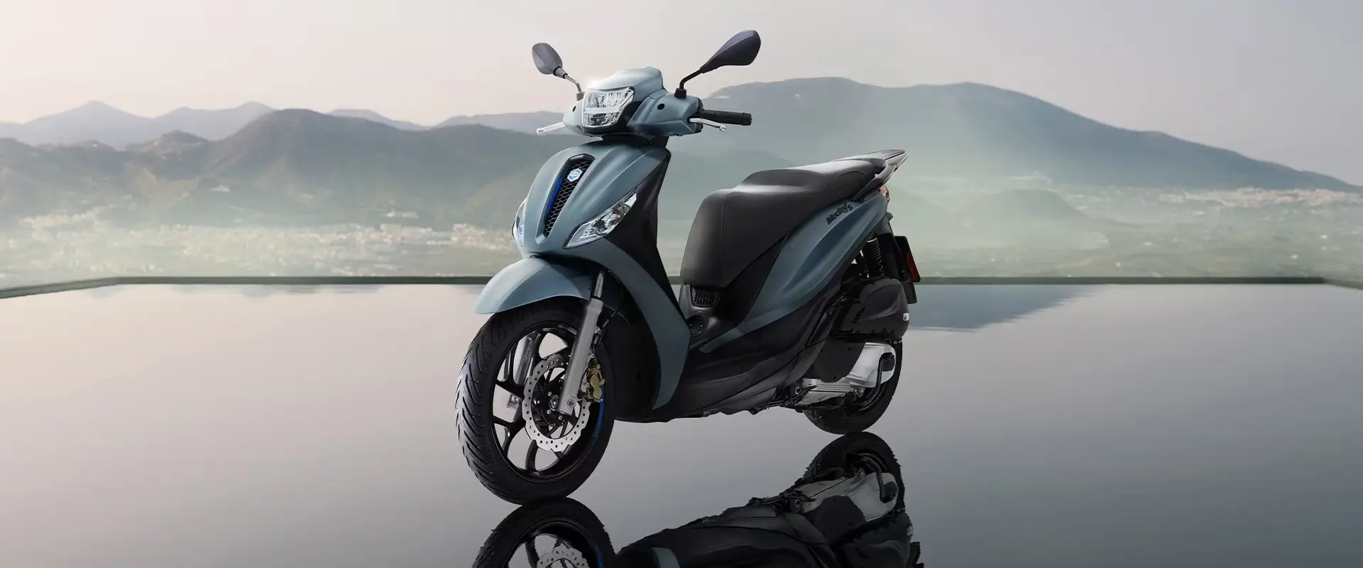 Ein Piaggio Medley Motorrad steht vor einer Berglandschaft.