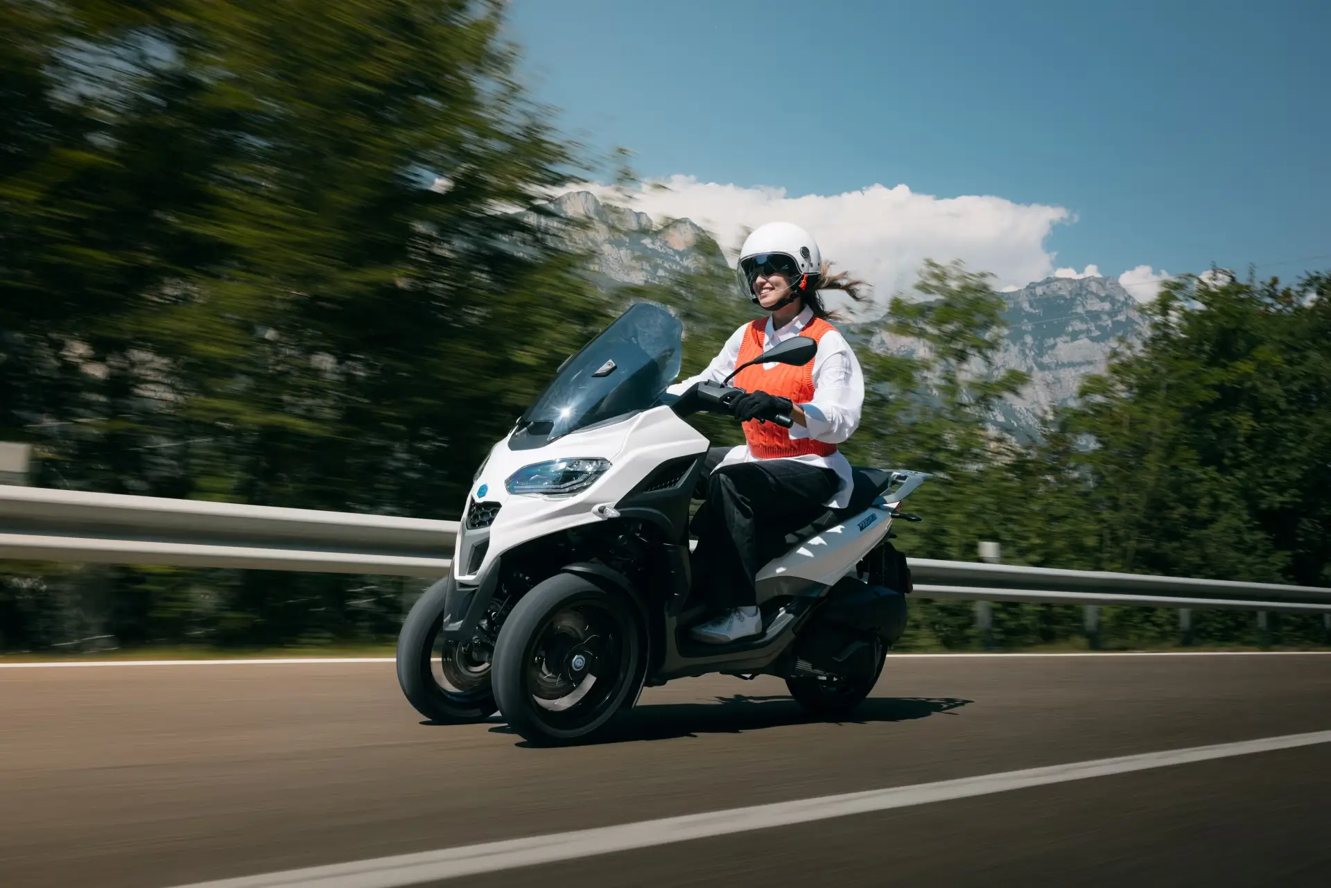 Eine Person fährt einen Piaggio Mp3 Roller auf einer Straße.