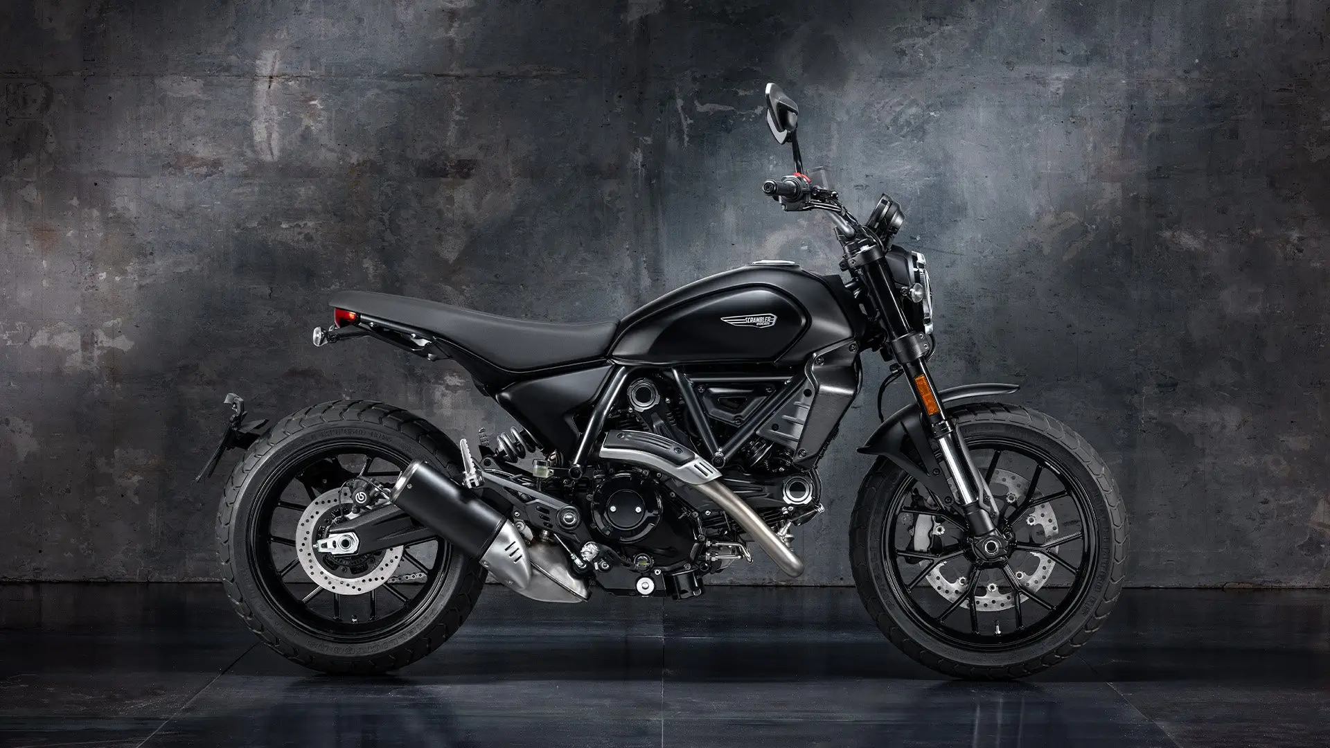 Schwarze Ducati Scrambler Icon Dark Motorrad vor grauem Hintergrund.