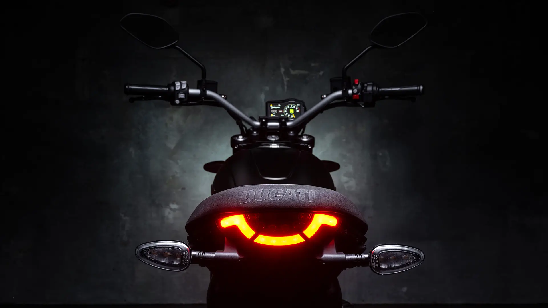 Rückansicht eines Ducati Scrambler Icon Dark Motorrads mit leuchtendem Rücklicht.