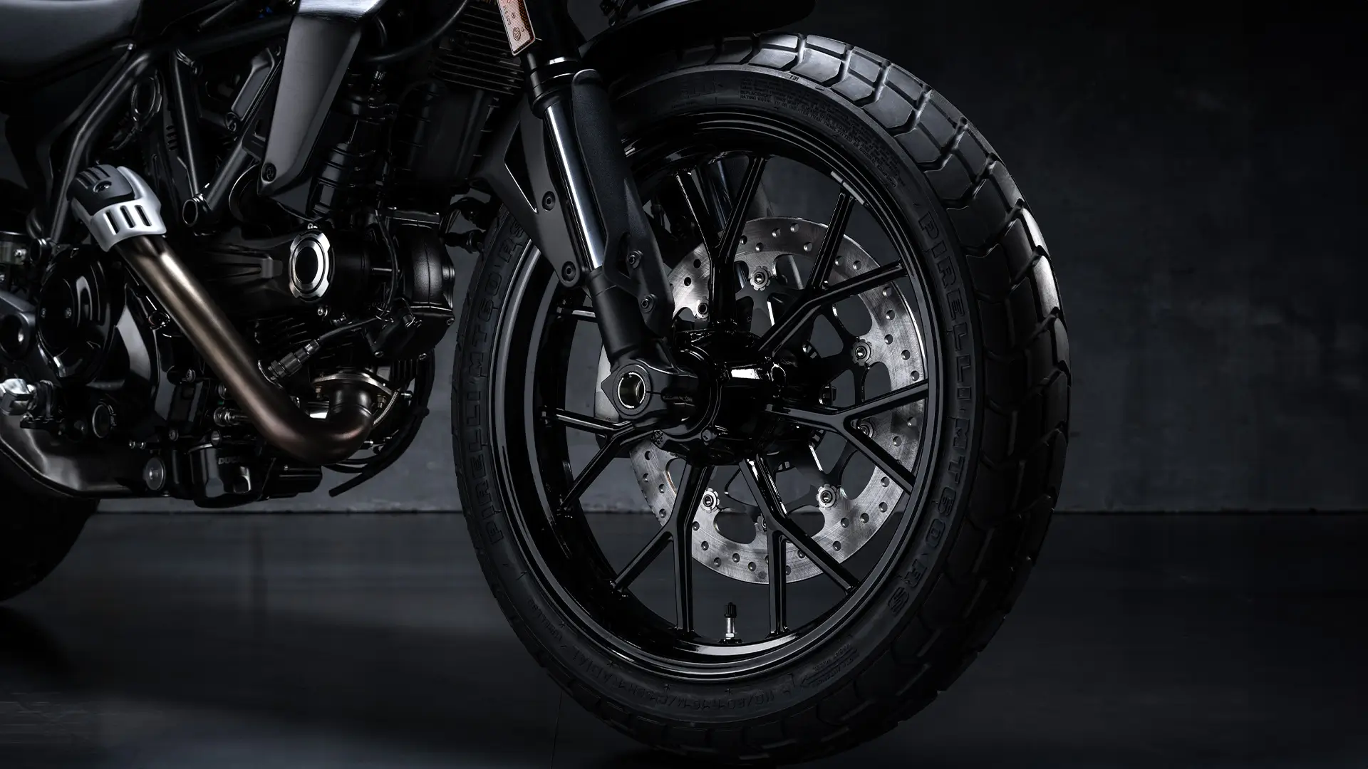 Vorderansicht eines Motorradreifens und -bremsscheibe einer Scrambler Icon Dark MY25.
