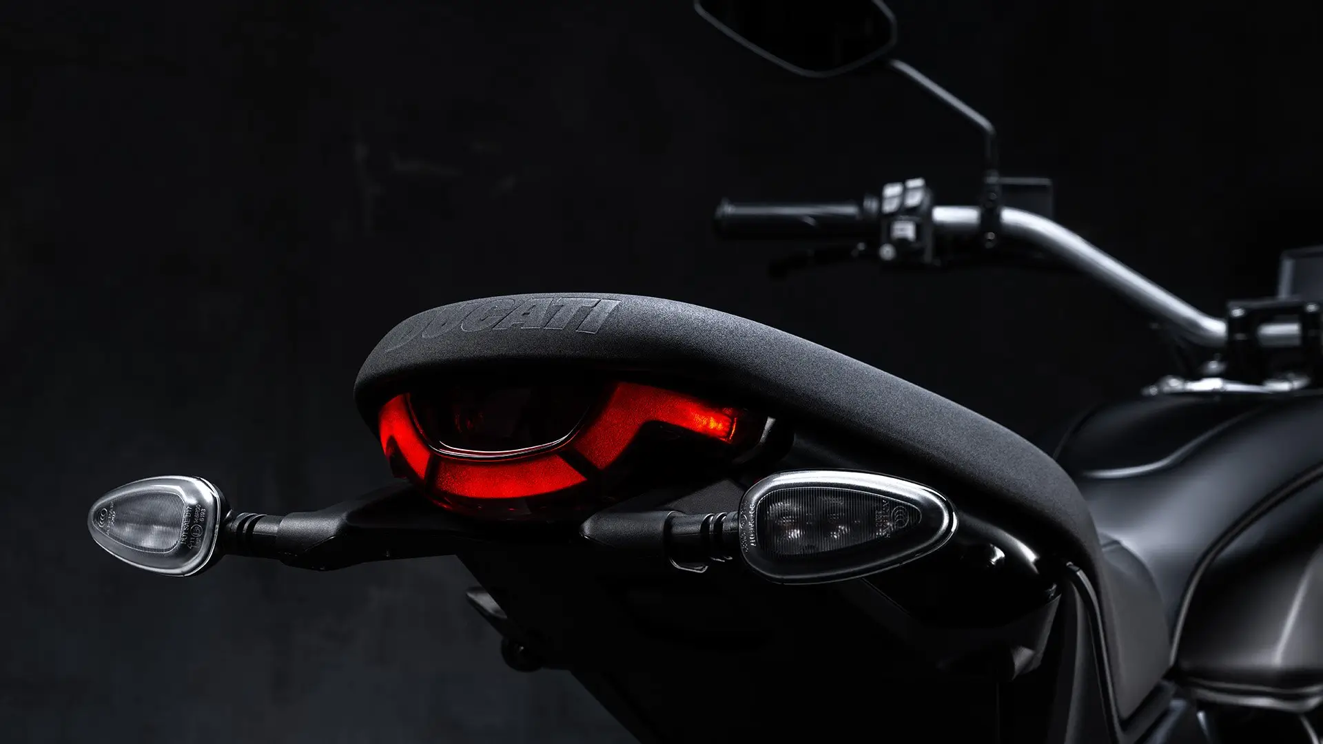Rückansicht eines Ducati Scrambler Icon Dark Motorrads mit leuchtendem Rücklicht.