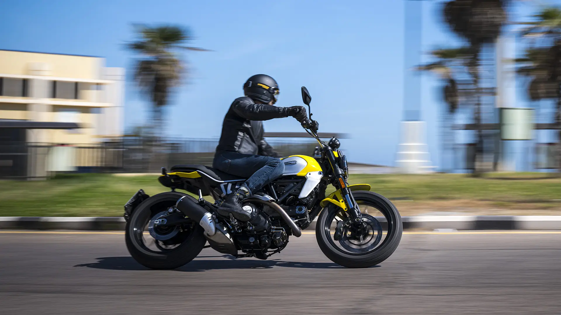 Ein Motorradfahrer fährt eine gelb-schwarze Scrambler Icon Next Gen auf einer Straße.
