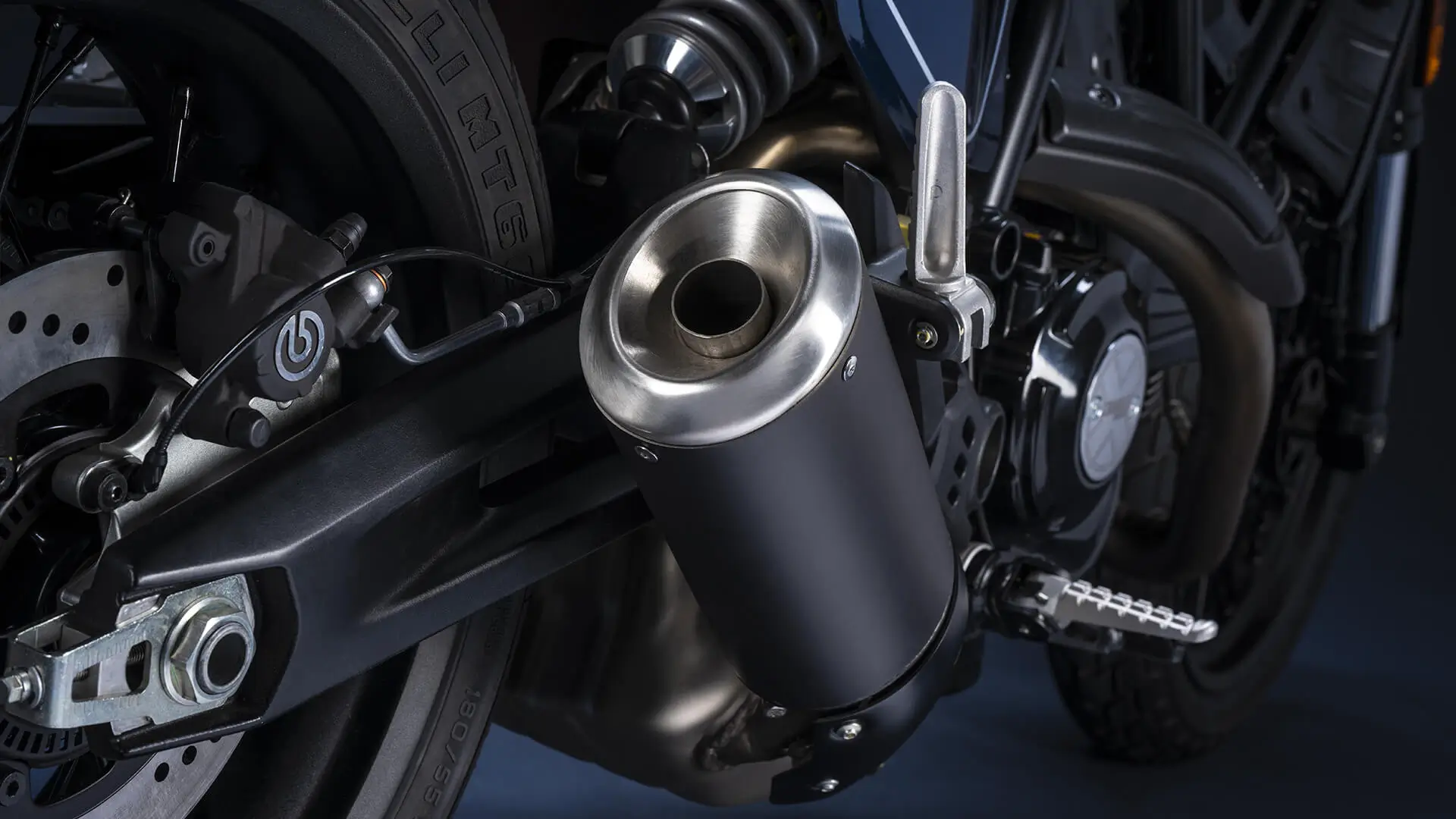 Auspuff und Hinterrad eines Motorrads, vermutlich eine Scrambler Nightshift.