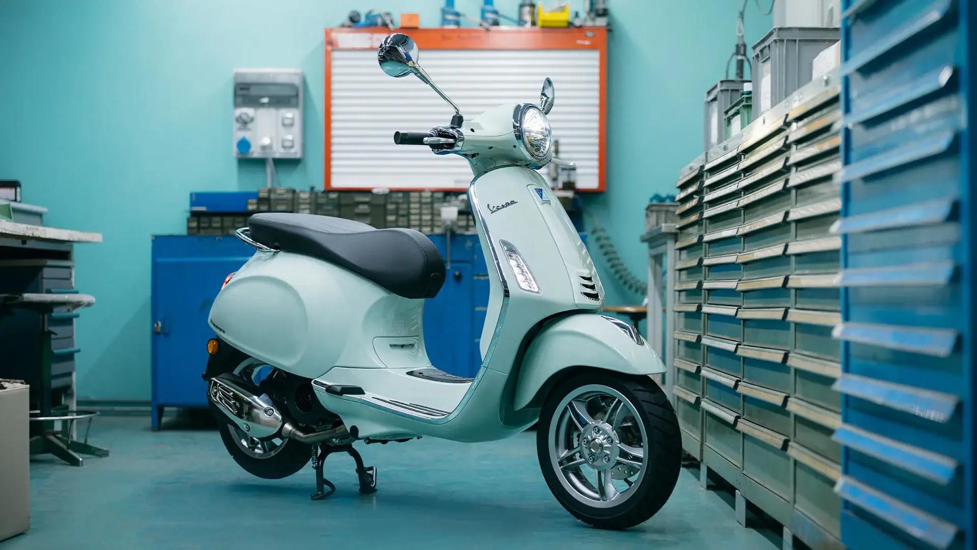 Eine Vespa Primavera steht in einer Werkstatt.