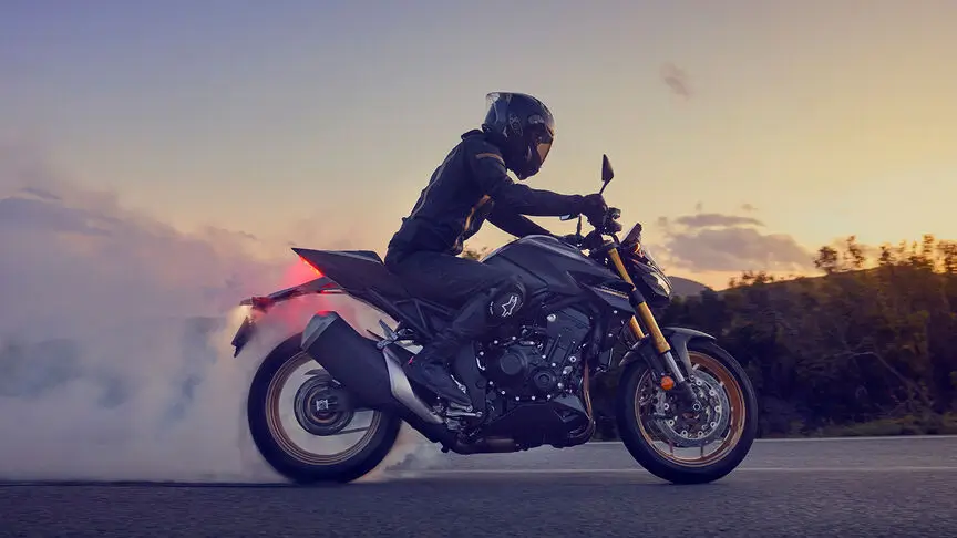 c4 (1) Ein Motorradfahrer auf einer CB1000 Hornet fährt bei Sonnenuntergang mit qualmendem Hinterreifen.
