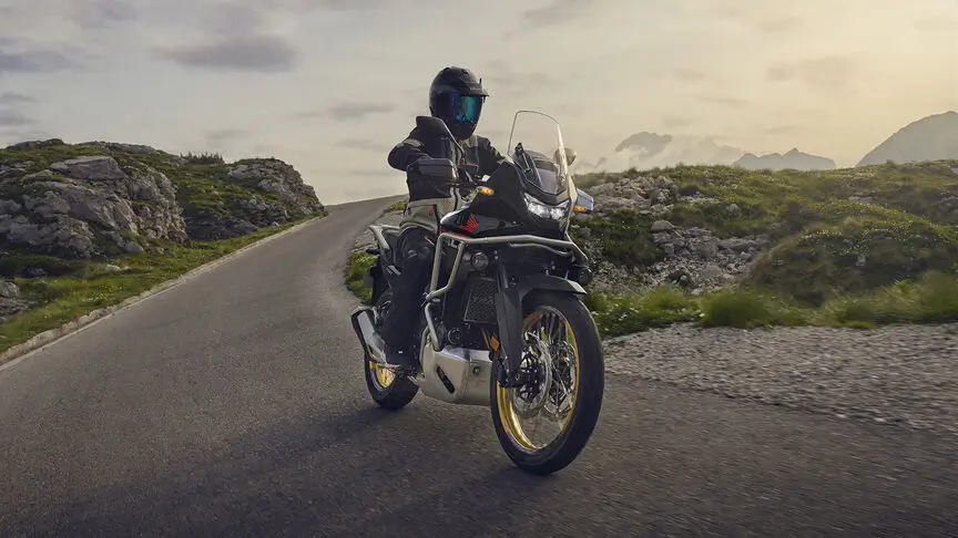 c4 (3) Ein Motorradfahrer auf einer kurvigen Bergstraße bei Sonnenuntergang.
