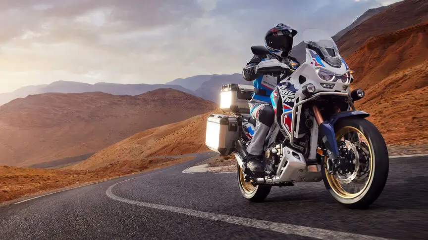 Ein Motorradfahrer fährt eine Honda Africa Twin auf einer kurvigen Bergstraße.