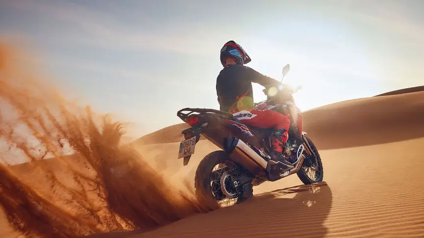 c4 Ein Motorradfahrer fährt mit einer Honda Honda Africa Twin durch eine Sanddüne.