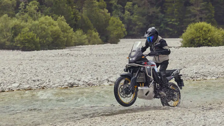 c4 Ein Motorradfahrer auf einer Suzuki V-Strom überquert einen flachen Fluss.