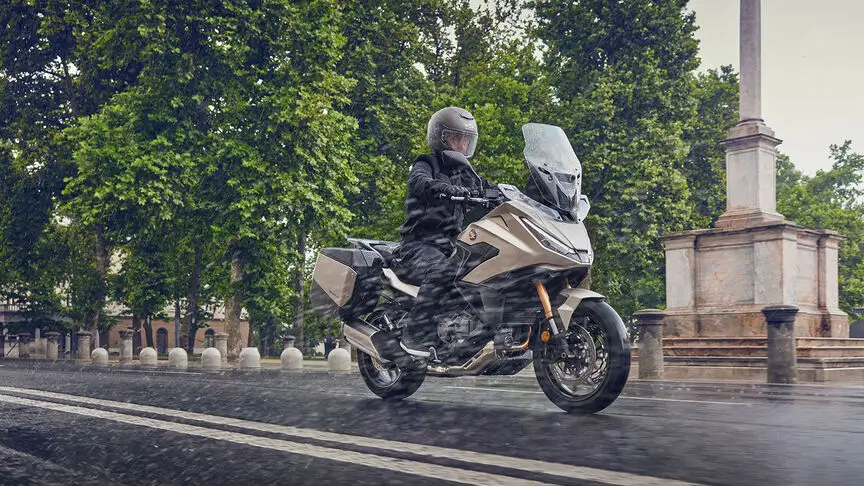 c4 Ein Motorradfahrer auf einer Honda NT1100 fährt bei Regen auf einer nassen Straße.