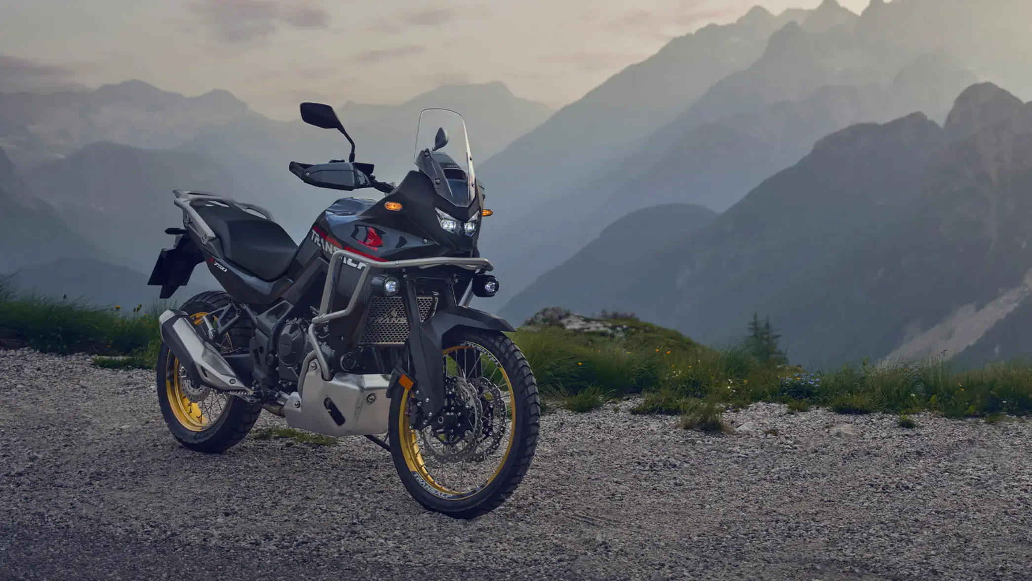 Ein Honda Transalp Motorrad steht vor einer Bergkulisse.