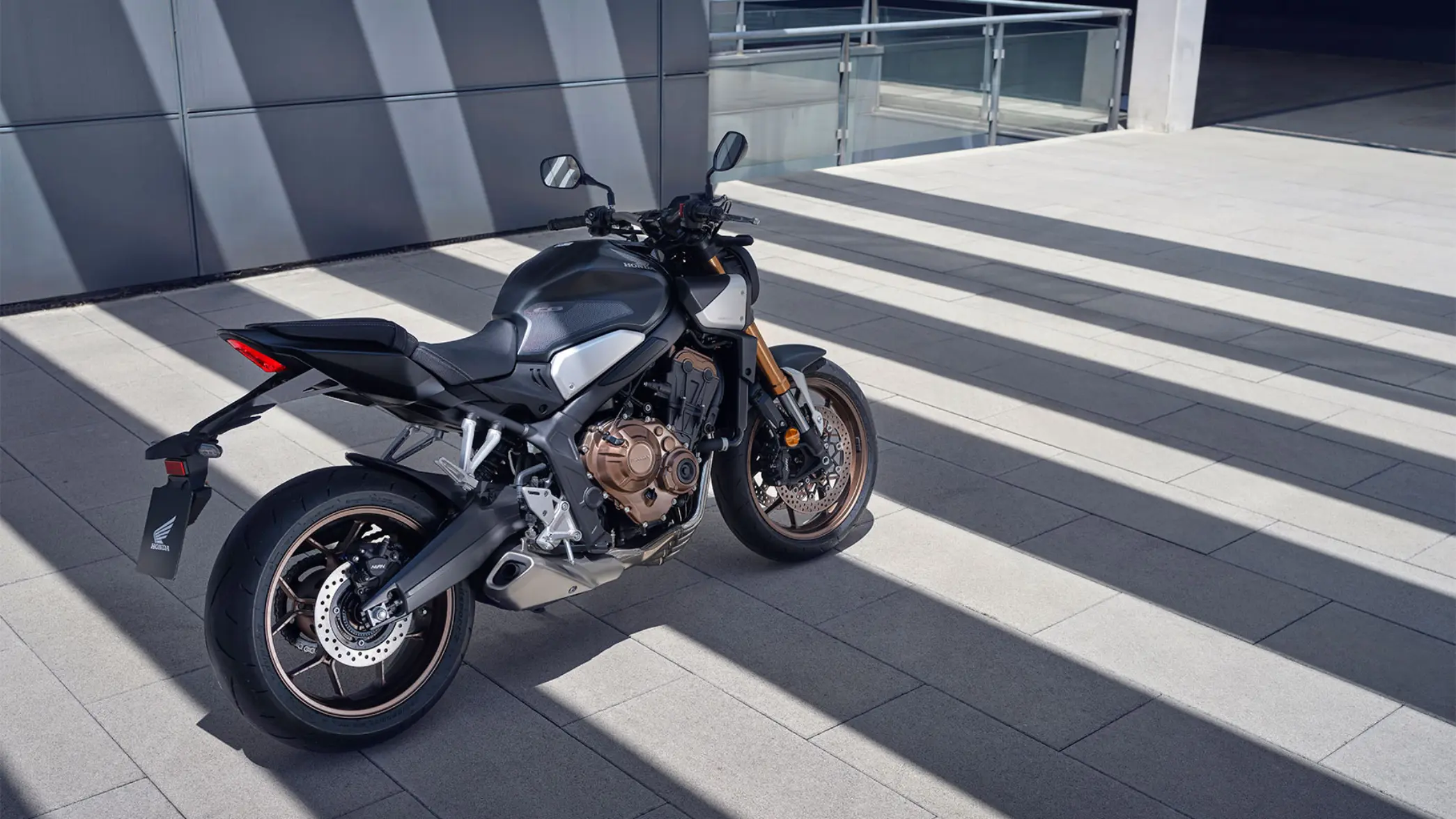 Ein Honda-Motorrad steht auf einem gepflasterten Platz im Sonnenlicht.