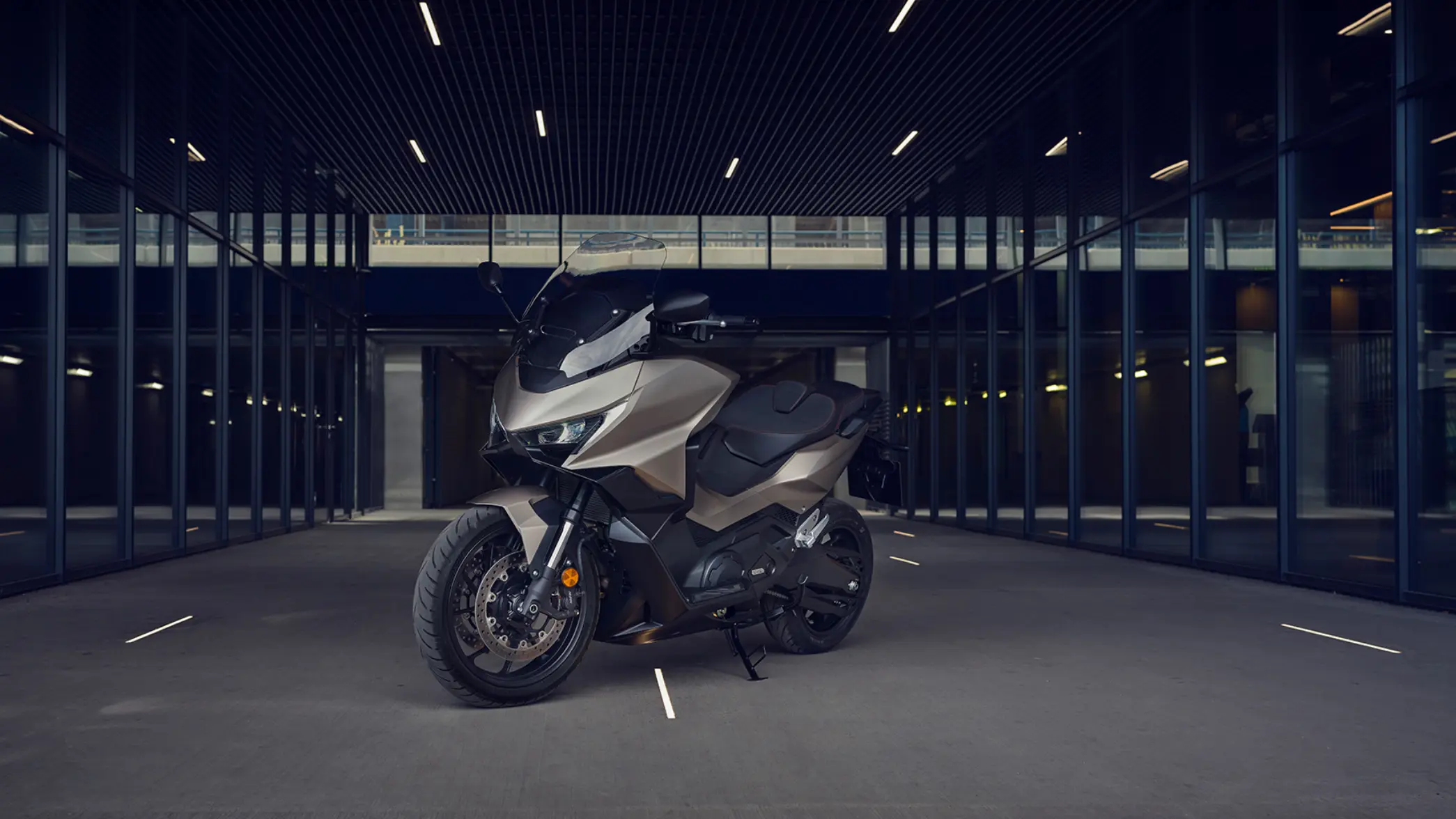 Ein modernes Motorrad Honda FORZA 750 steht in einem überdachten Bereich mit Glaswänden.