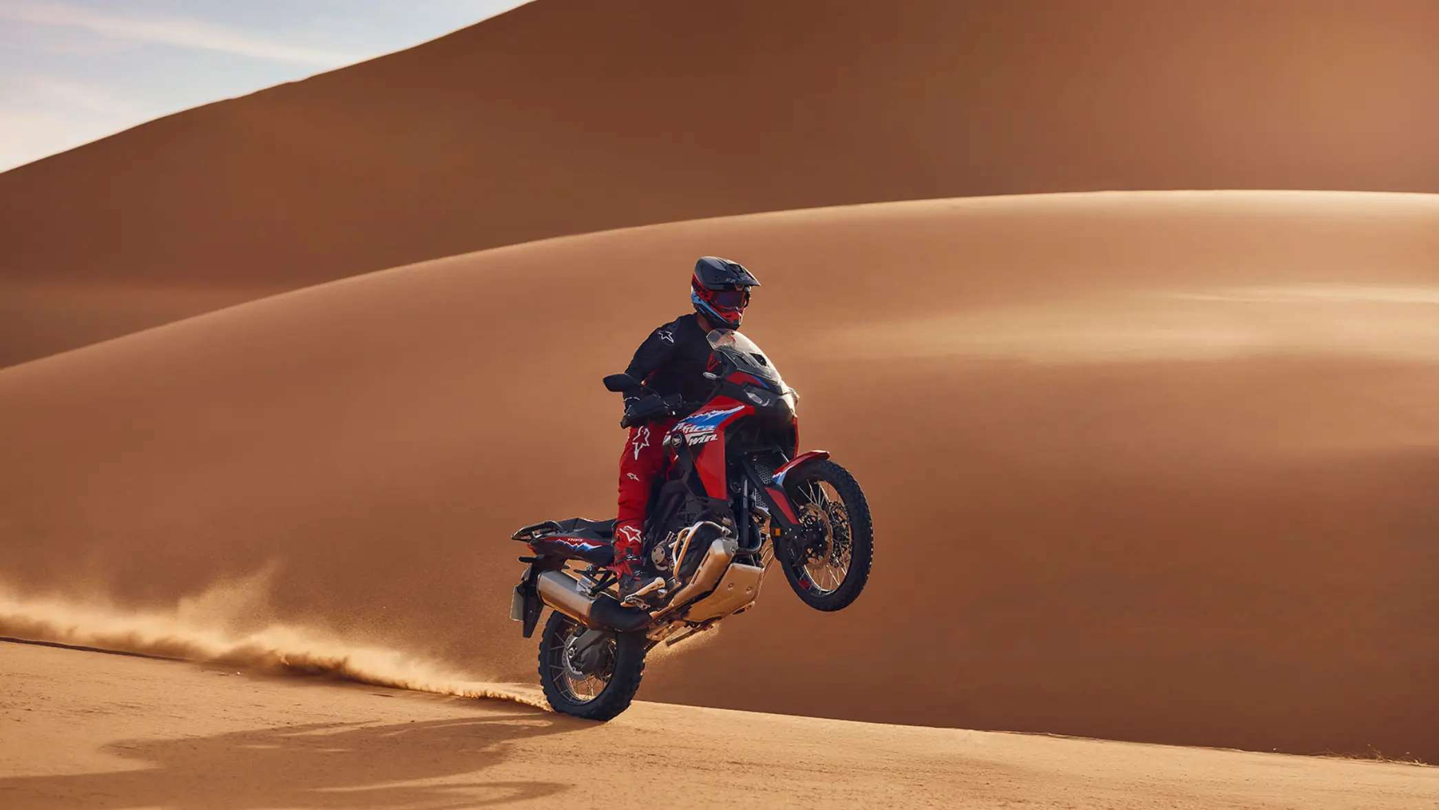 Ein Motorradfahrer springt mit einer Honda Africa Twin durch die Wüste.