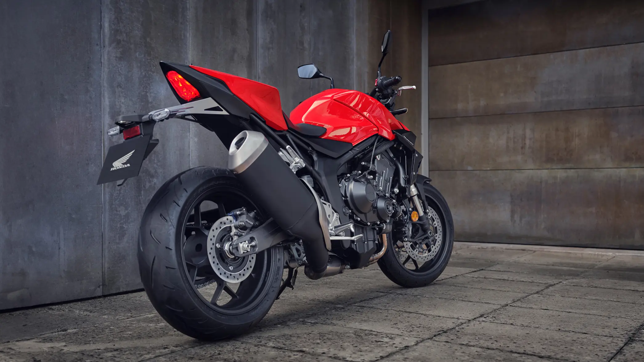 Rotes Honda-Motorrad CB1000 Hornet, Seitenansicht in einer urbanen Umgebung.