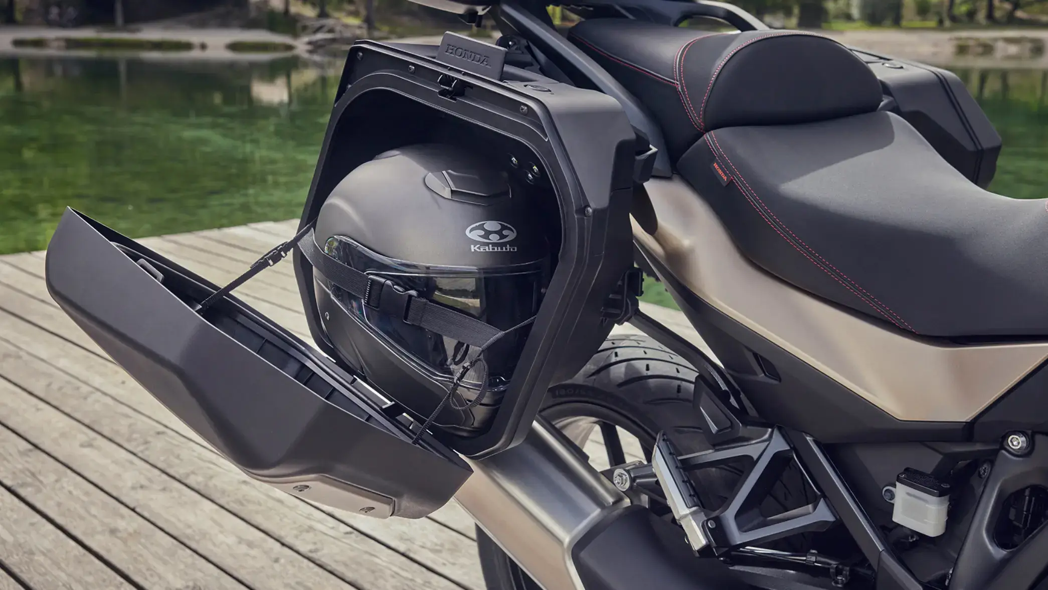Ein Motorradhelm der Marke Kabuto ist in einem geöffneten Seitenkoffer eines Honda-Motorrads verstaut.