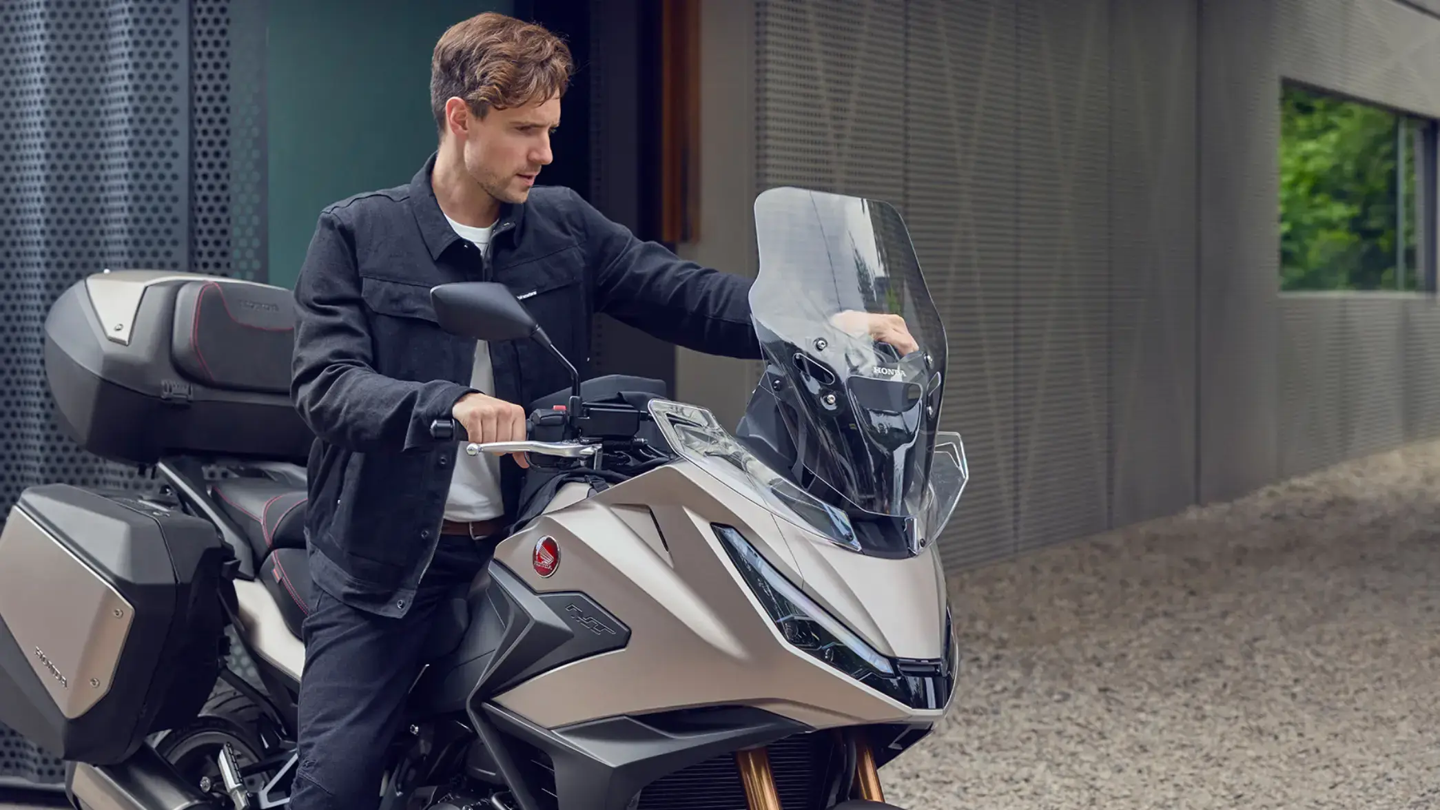 Ein Mann steht neben einem Honda-Motorrad Honda Honda NT1100 und hält den Lenker.
