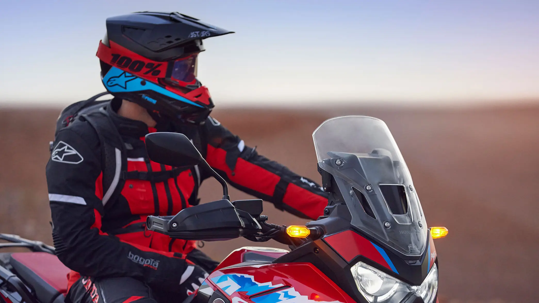Motorradfahrer in roter Schutzkleidung auf einer Honda mit Helm und Visier.