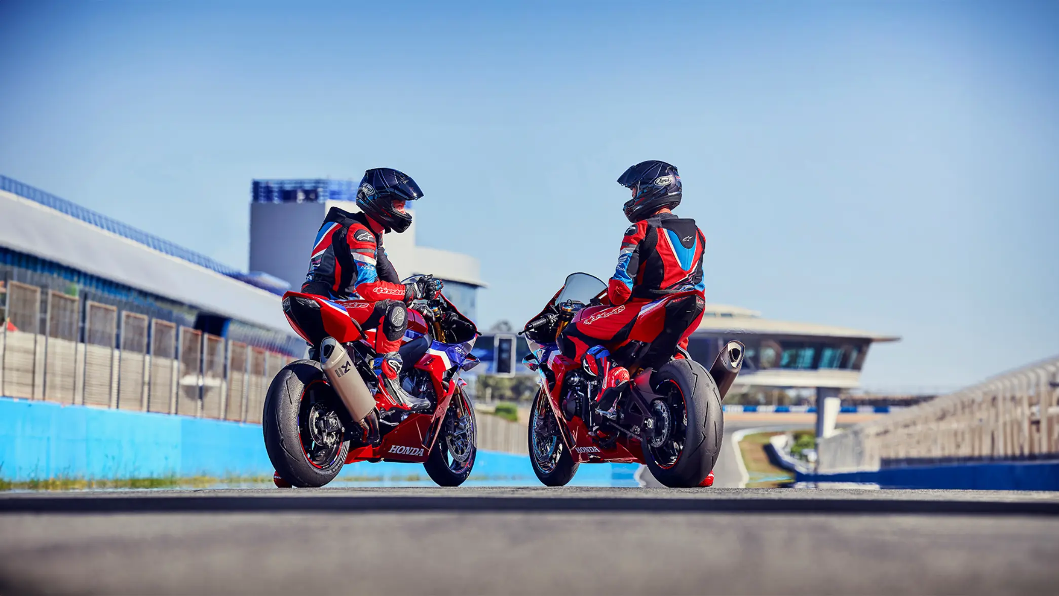 Zwei Motorradfahrer auf Honda CBR1000RR-R Fireblades in Rennbekleidung auf einer Rennstrecke.