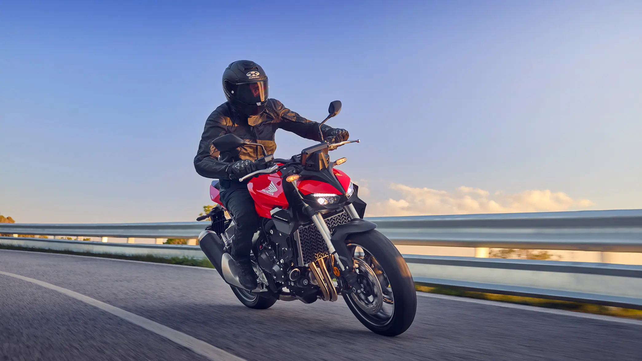 Ein Motorradfahrer auf einer roten Honda fährt auf einer Straße.
