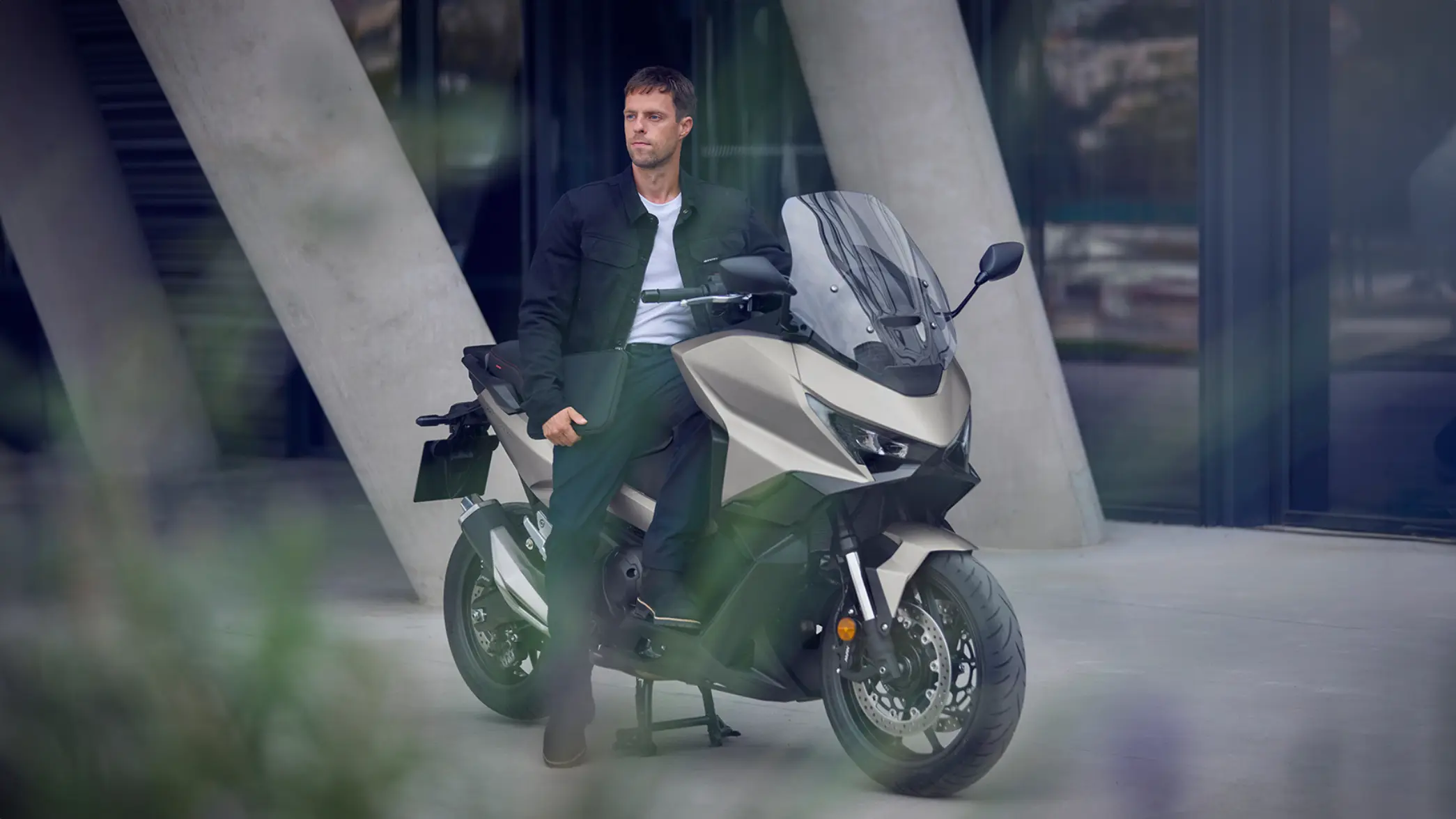 Ein Mann sitzt auf einem modernen Motorrad FORZA 750 vor einem Gebäude.