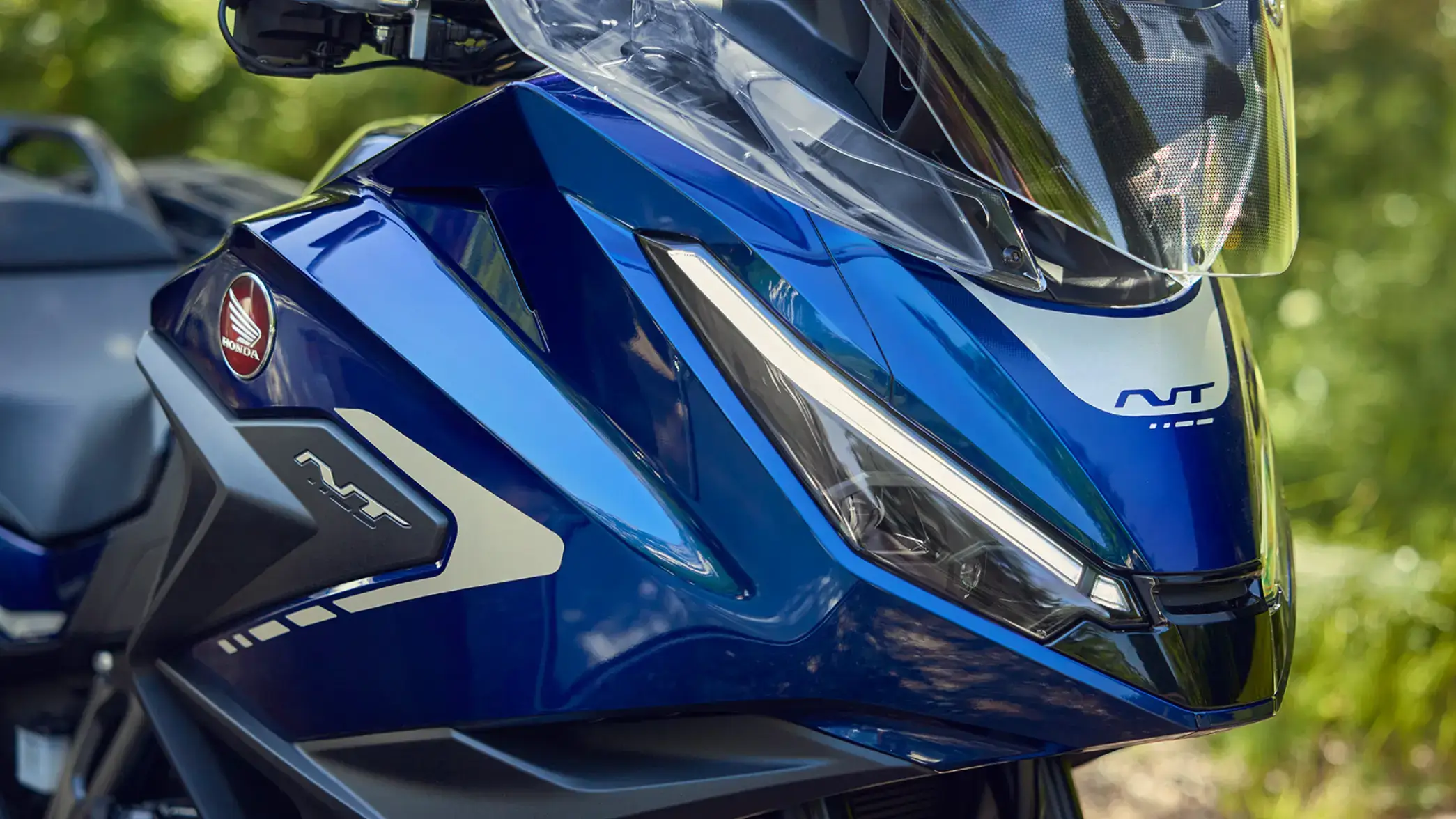 Nahaufnahme eines blauen Honda NT Motorrads mit sichtbarem Logo und Scheinwerfer.