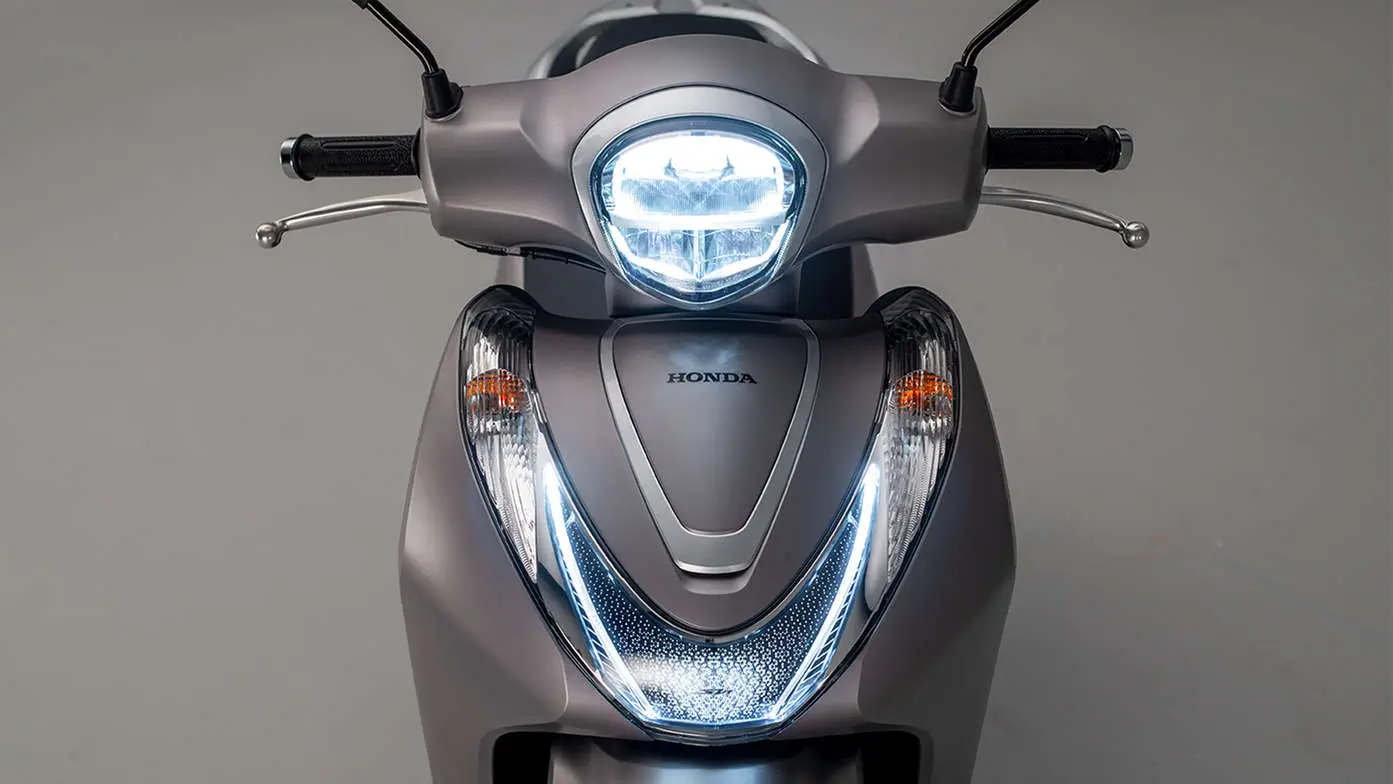 Honda SH Mode 125 Roller von vorne mit eingeschaltetem Scheinwerfer.